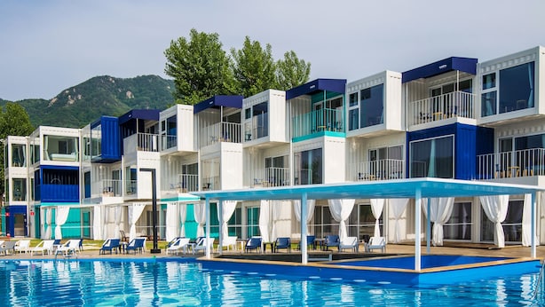 Un hotel con area piscina, diversi balconi e vista sulle montagne.