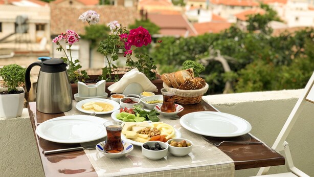 A table set with various dishes and a view of a coastal town. - Kastoria Butik Pansiyon (Ayvalik)