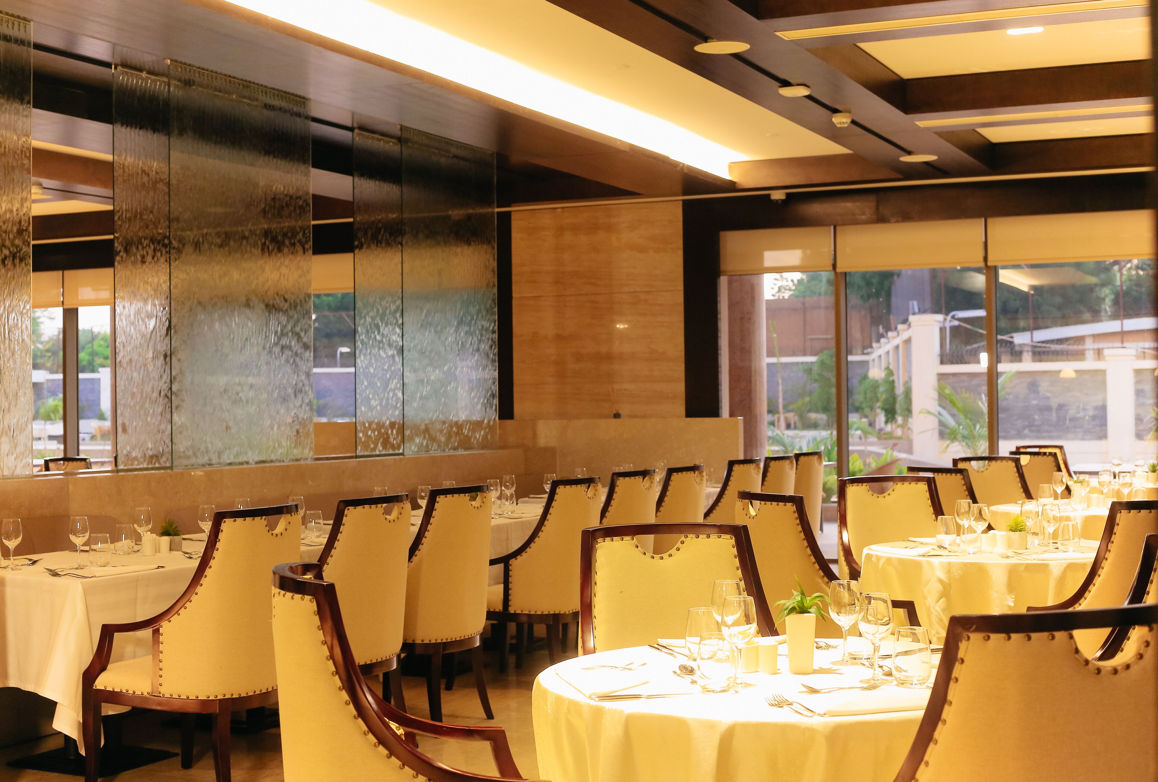 Un restaurante con mesas y sillas redondas, ventanas amplias y una decoración interior moderna.