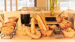 Un bufé de desayuno con panes, bollería y bebidas variadas.