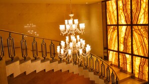 Una imponente escalera con candelabro, paredes de mármol y un amplio ventanal con vista decorada.