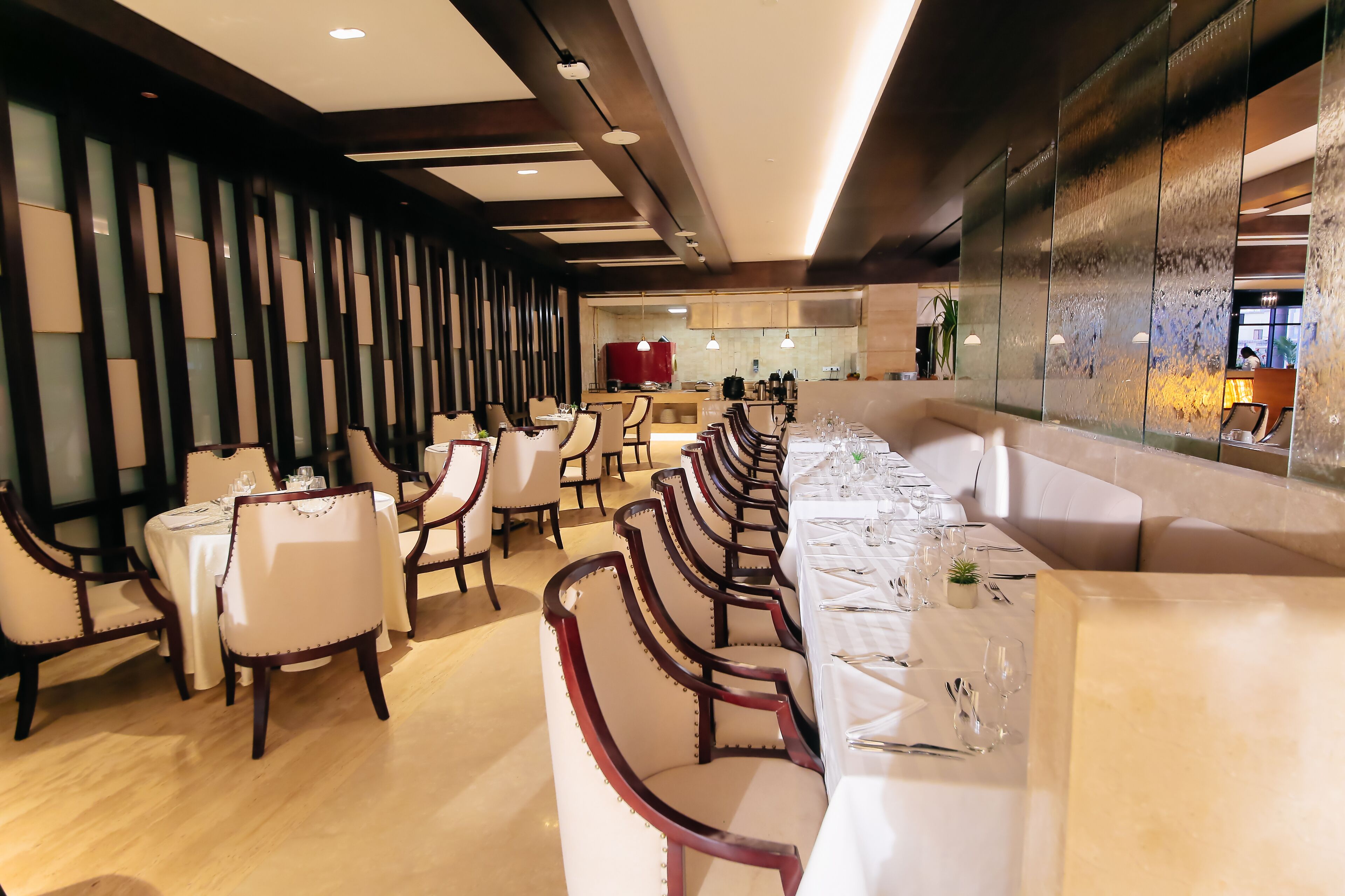 Un restaurant avec de longues tables, des chaises blanches et un décor intérieur moderne.