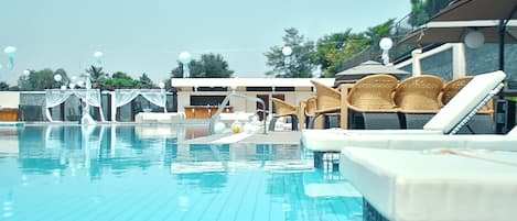 Una piscina al aire libre, sombrillas, sillones reclinables de piscina