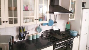 Una cocina con armarios blancos, una estufa negra y un refrigerador blanco.