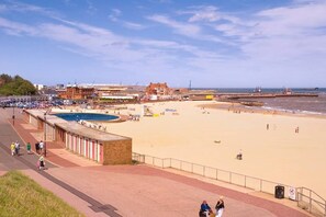 A beach with a pool, a promenade, and buildings in the background. - Gorgeous Gorleston Edwardian terraced house (Gorleston on Sea)