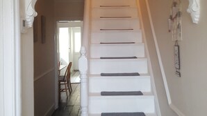 Una escalera blanca con barandilla de madera que lleva a un rellano con una puerta.