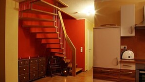 A compact kitchen with a wooden cabinet, a white refrigerator, and a staircase leading to a red room. - Ferienhaus Thormarcon (Goehren-Lebbin)