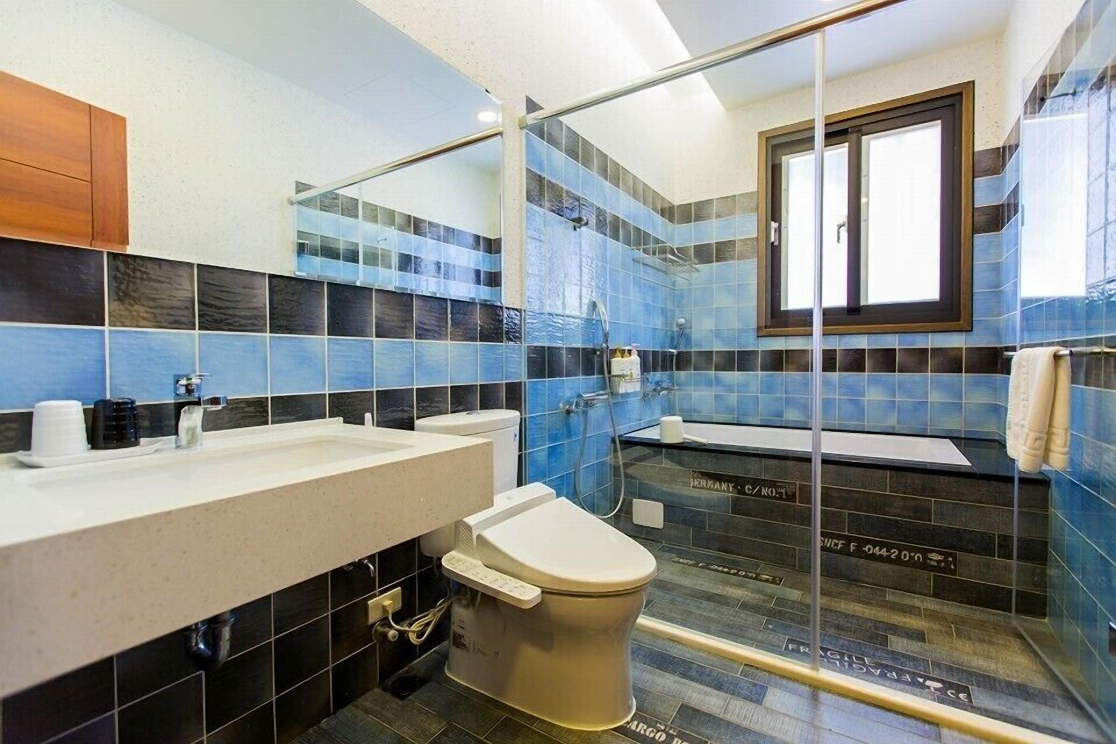 A modern bathroom with a glass-enclosed shower, a toilet, and a sink.