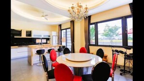 A modern kitchen with white cabinets, a central island, and a dining area with red chairs. - Relax B&B (Dongshan)