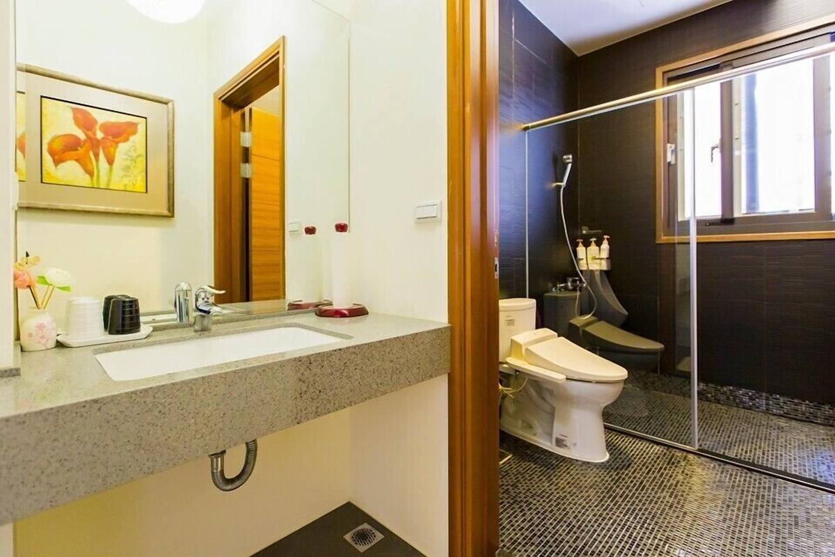 A modern bathroom with a granite countertop, a white sink, a mirror, and a glass-enclosed shower area.