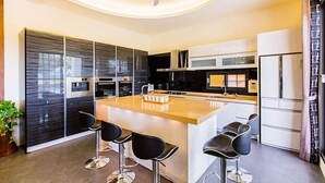 A modern kitchen with a central island, bar stools, and built-in appliances. - Relax B&B (Dongshan)