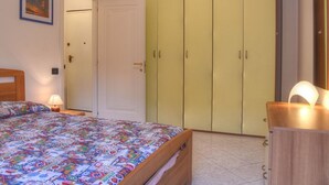 Ein Schlafzimmer mit einem Bett, einem Kleiderschrank, einem Nachttisch und einer Nachttischlampe.