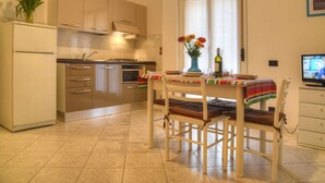 Eine Küche mit Esstisch, Stühlen, Kühlschrank und Fernseher.