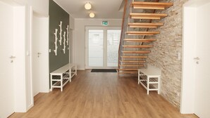 Un interior moderno con una escalera de madera, paredes blancas y una pared de acento de ladrillo.