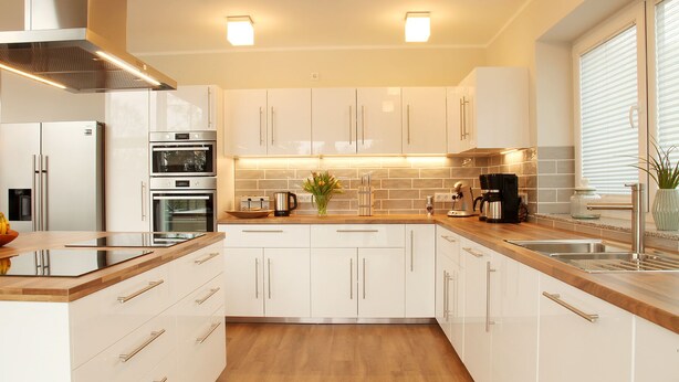 Una cocina moderna con armarios blancos, electrodomésticos de acero inoxidable y encimeras de madera.
