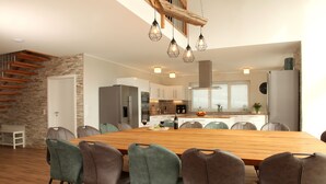 Una cocina moderna con una mesa de comedor de madera, sillas y lámparas colgantes.
