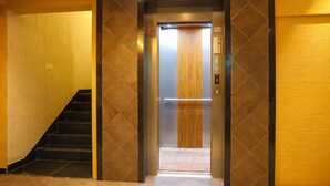 An elevator with a wooden panel and a control panel.