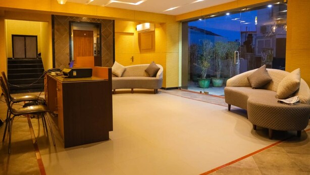 A modern living room with a sofa, a small desk, and a chair. There is a staircase leading to an upper level.