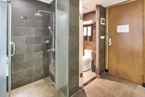 A bathroom with a shower, toilet, and a wooden door. - Jiangxia Business Hotel (Guangzhou)