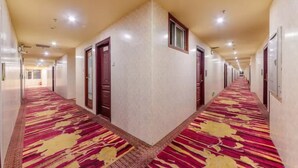 A long, narrow hotel corridor with a patterned carpet and doors on both sides. - Jiangxia Business Hotel (Guangzhou)