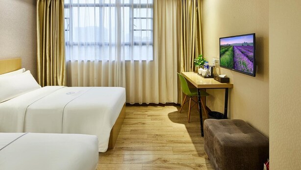 A hotel room with two beds, a desk with a chair, a television, and a window with curtains. - Jiangxia Business Hotel (Guangzhou)