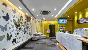 A hotel lobby with a reception desk, a seating area, and a wall decorated with butterfly patterns. - Jiangxia Business Hotel (Guangzhou)
