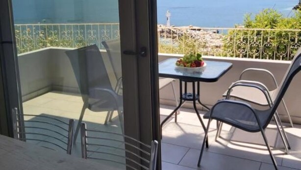 A balcony with a table and chairs, overlooking a lake and mountains. - Villa Maria Sea View by Estia (Mylopotamos)