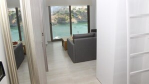 A modern living room with a grey sofa, a coffee table, and a view of the sea through large windows. - Villa Maria Sea View by Estia (Mylopotamos)