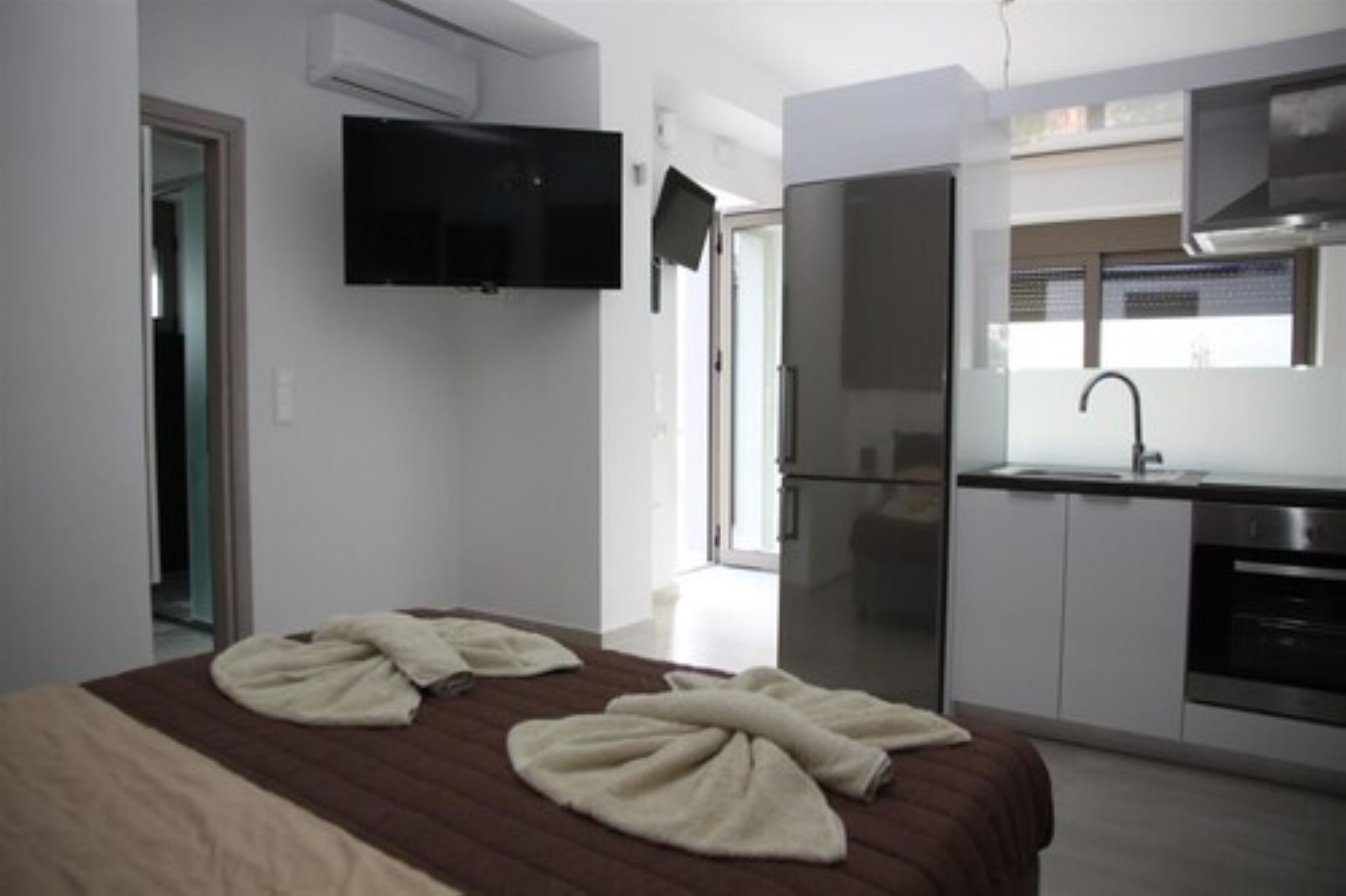 Habitación de hotel moderna con cama, televisor de pantalla plana, kitchenette y baño.