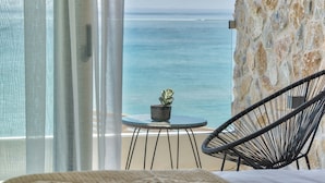 Un balcón con vista al mar, una planta en maceta y una silla.