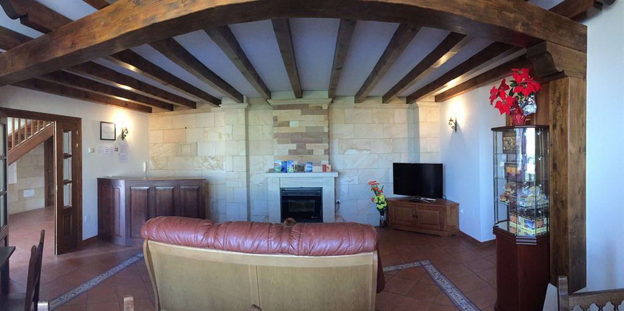A living room with a stone fireplace, a television, and a glass display cabinet.