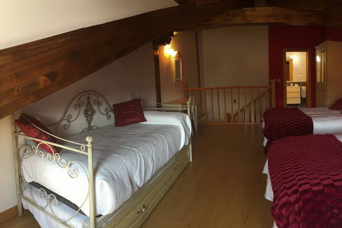 Ein Schlafzimmer mit zwei Betten, Holzbalken und einer Treppe, die zu einem Badezimmer führt.