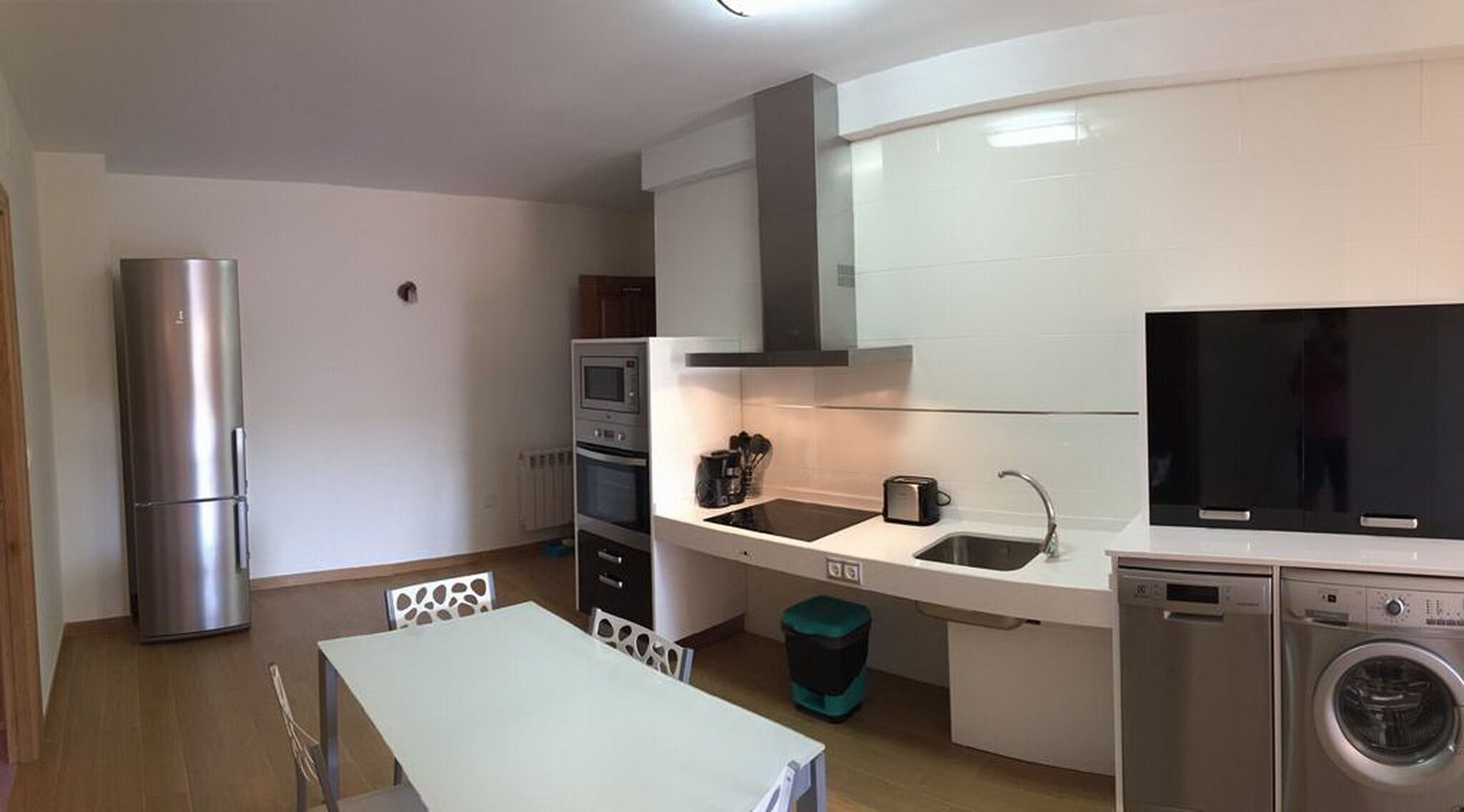 Eine kleine Küche mit Kühlschrank, Backofen, Mikrowelle, Spüle und Waschmaschine.