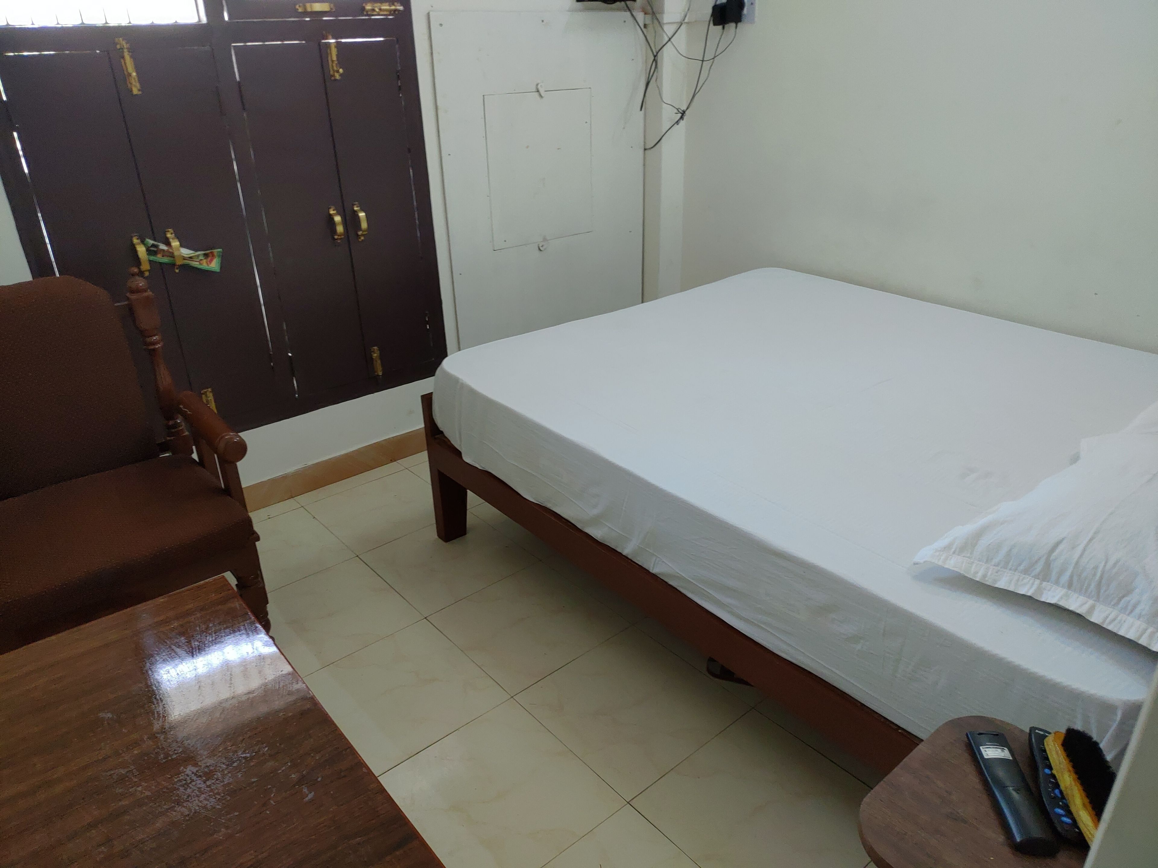 A room with a bed, a wooden chair, a small table, and a wardrobe.