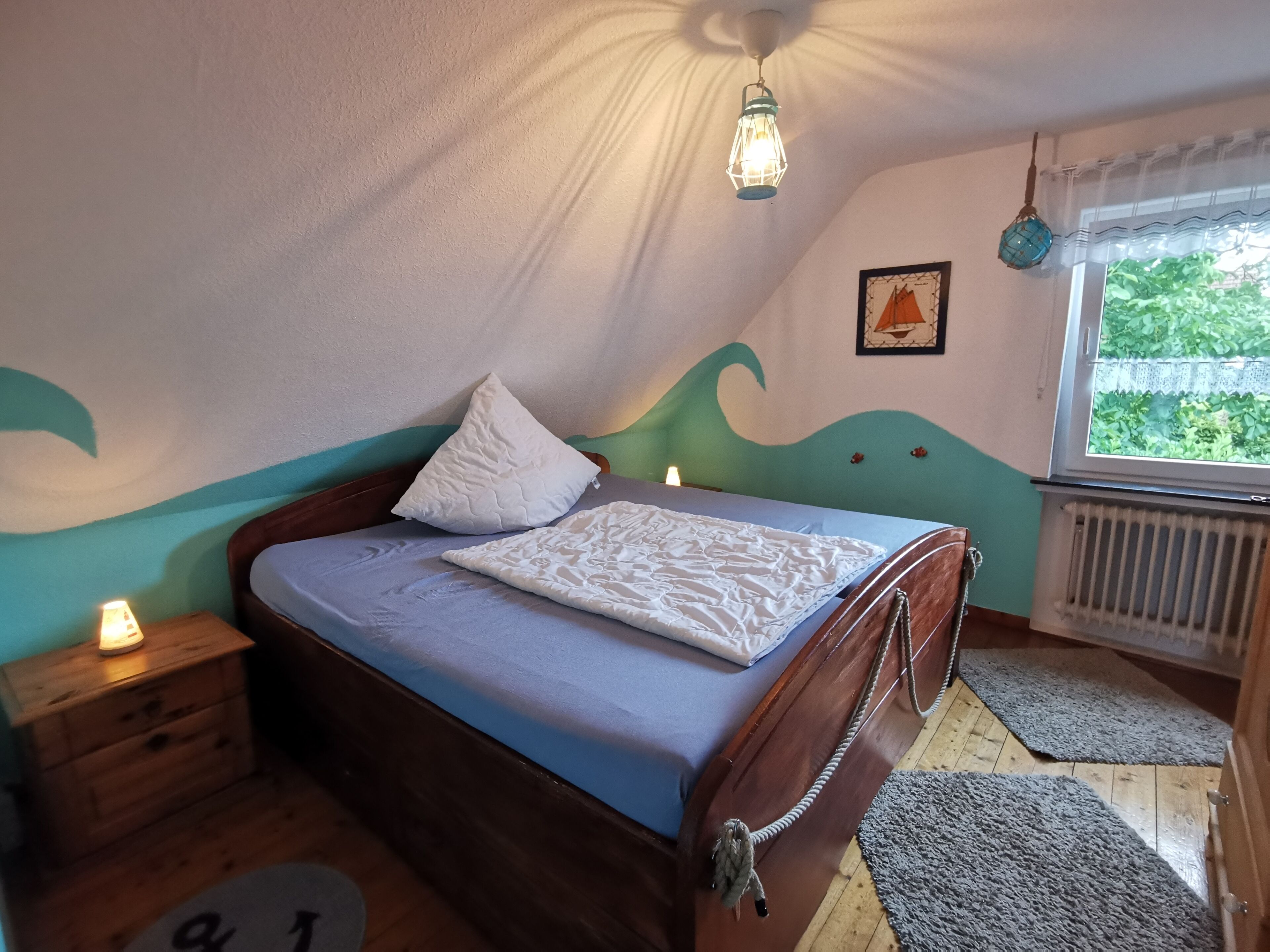 A bedroom with a bed, a nightstand, a window with a view, and a wall with a wave design.