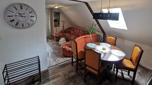 Un coin repas avec une table ronde, des chaises et une horloge au mur.