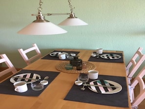 A dining table set with plates, cutlery, and glasses, with a placemat and a bottle of water. - Fewo Wiesenreich - Sophienhof New Heinde (Prebberede)