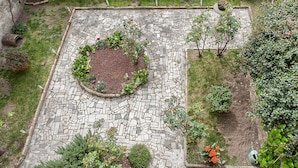 A courtyard with a stone-paved area, surrounded by greenery and potted plants. - San Frediano Apartment (Florence)