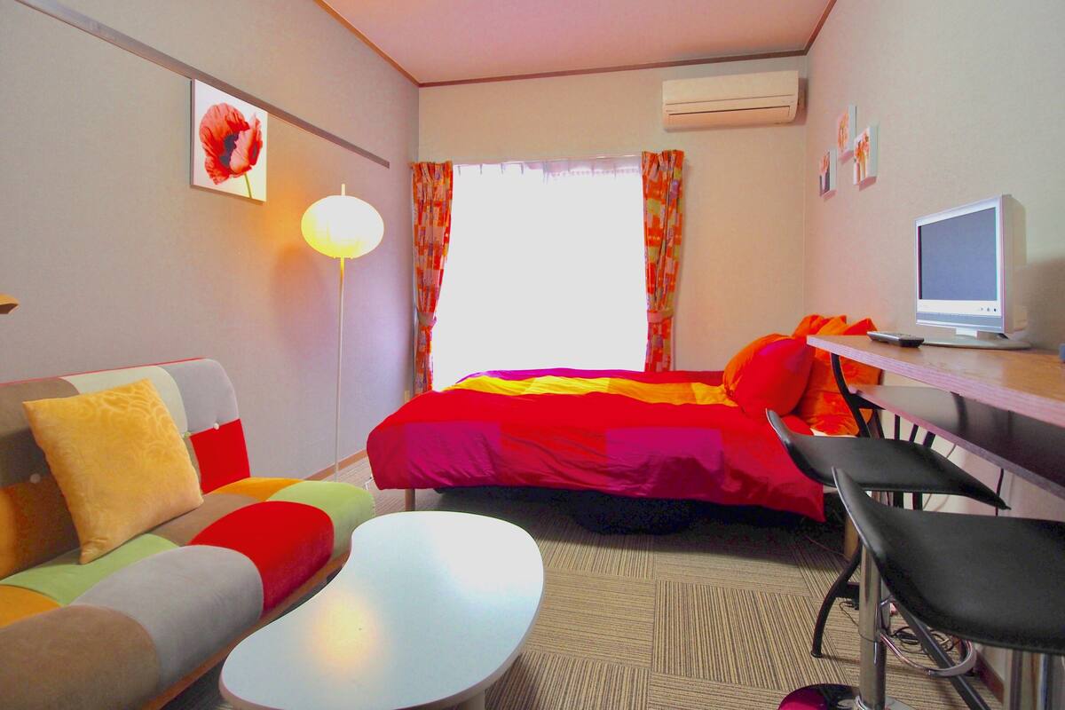 A hotel room with a bed, a desk with a computer, a sofa, and a chair.