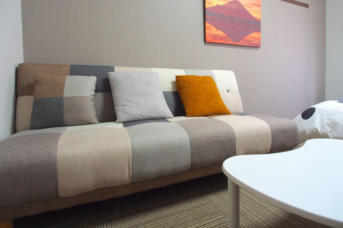 A modern living room with a sofa, a coffee table, and a painting on the wall.
