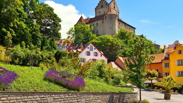 A historic castle with a turret, surrounded by colorful houses and lush greenery. - Das Nest am Wohrenberg (Daisendorf)