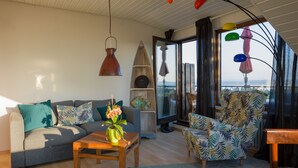 A modern living room with a sofa, armchair, and coffee table. There is a large window with a view of the outdoors. - Das Nest am Wohrenberg (Daisendorf)