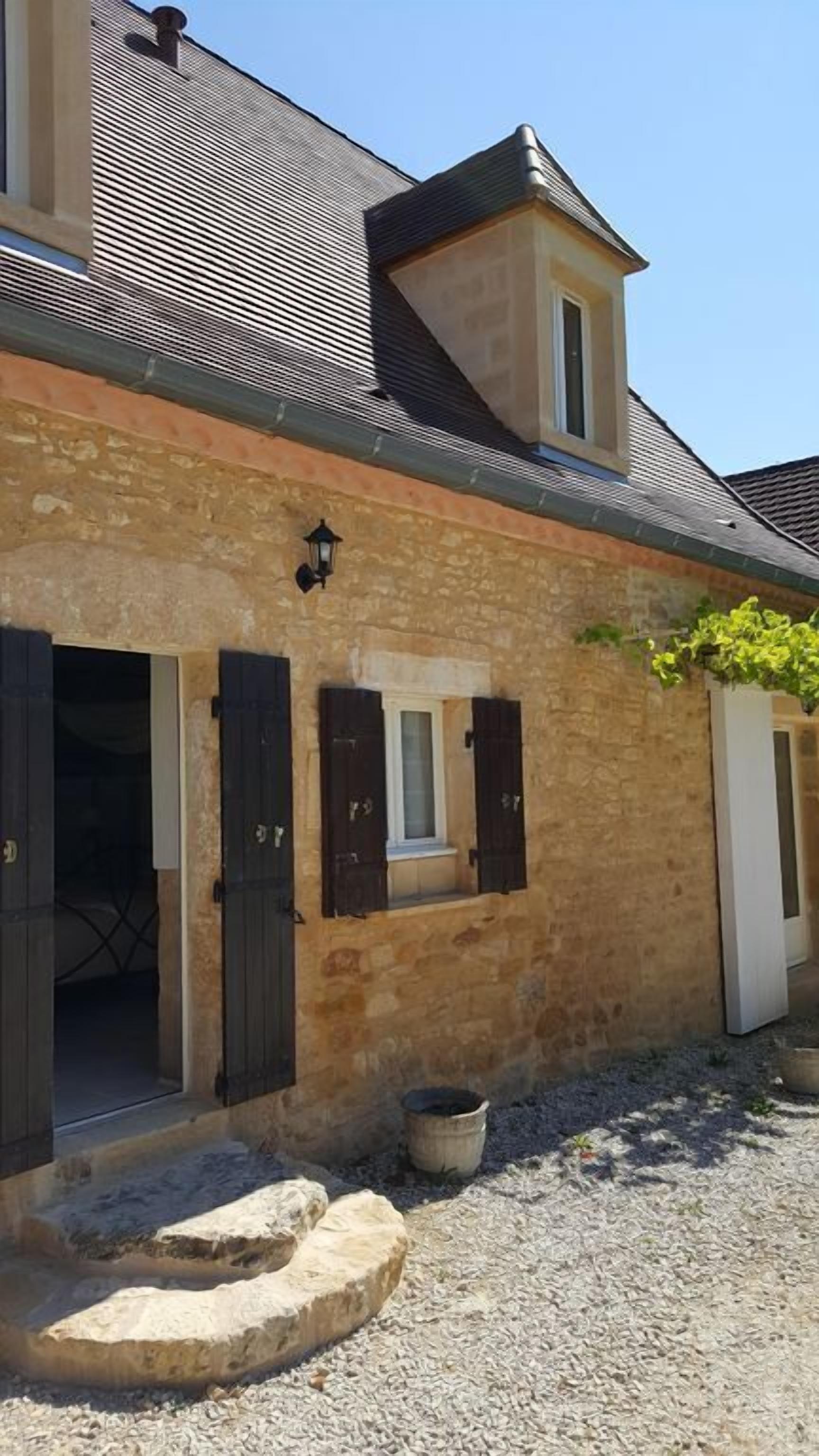 A stone building with a sloped roof, a small window, and a door with shutters.