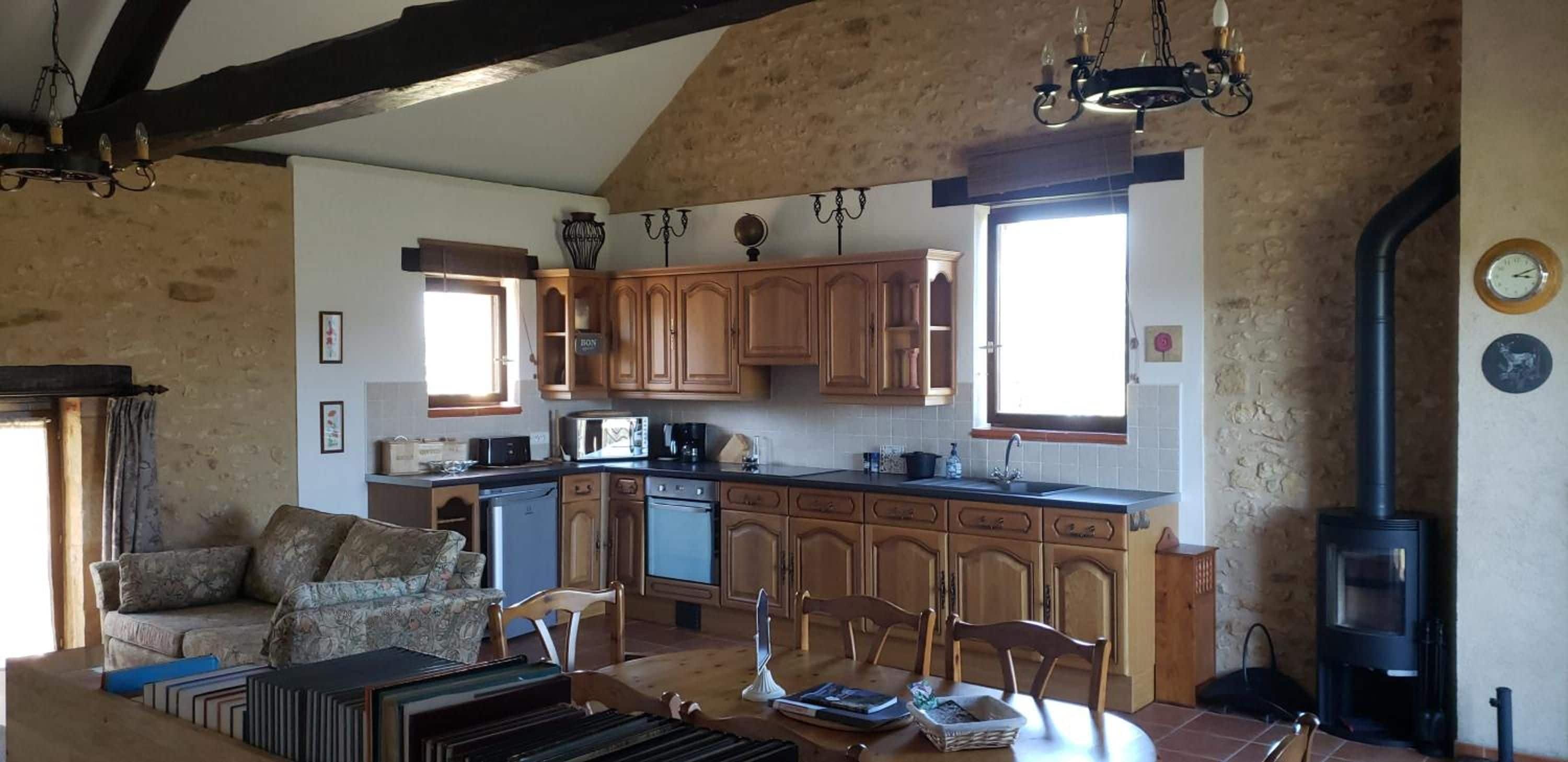 A cozy kitchen with wooden cabinets, a dining table, and a black wood stove.