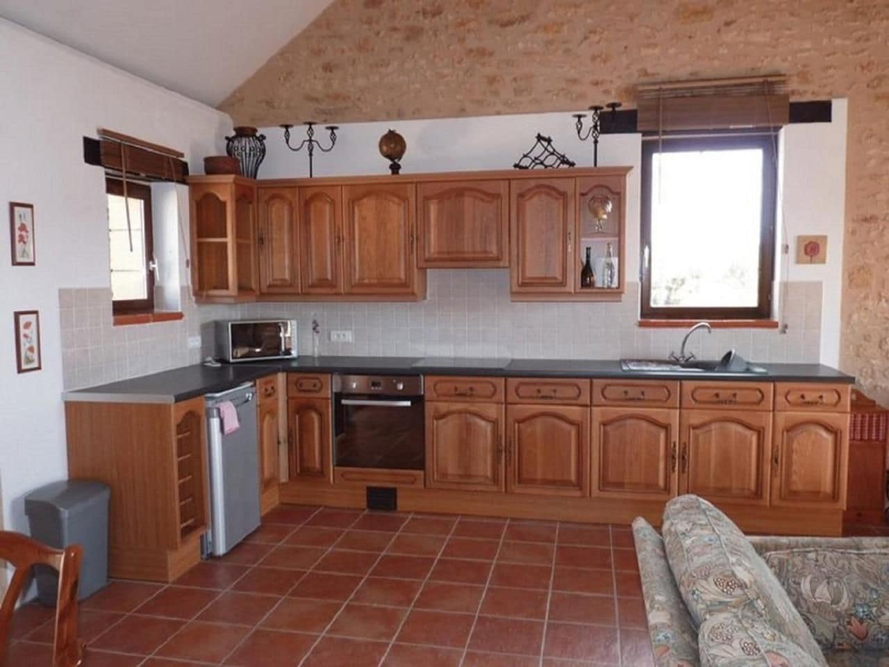 Une cuisine avec des meubles en bois, un four encastré, un évier et une fenêtre donnant sur un beau paysage.