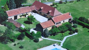 An aerial view of a large house with a swimming pool, surrounded by well-maintained lawns and trees. - Domaine de Manilau - B&B (Le Buisson-de-Cadouin)