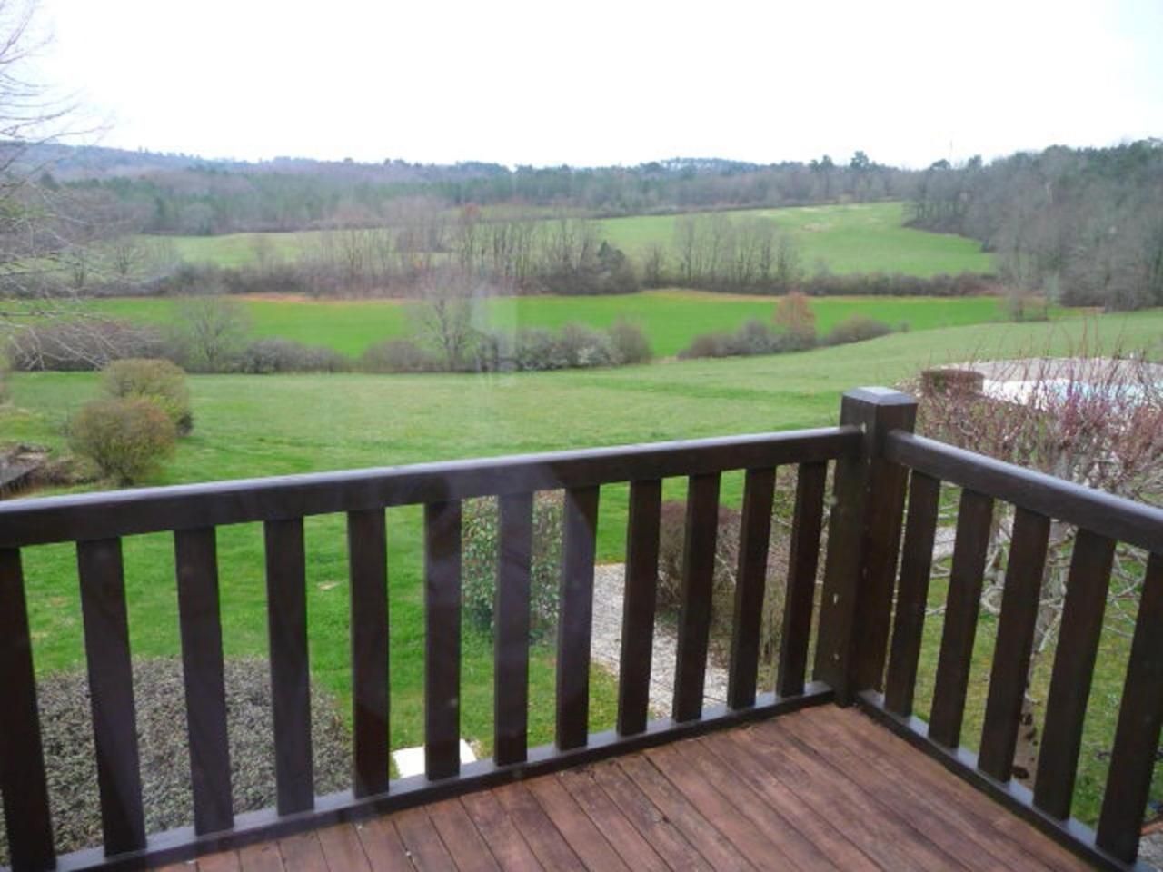 Una terraza de madera con vista a un campo verde y árboles.