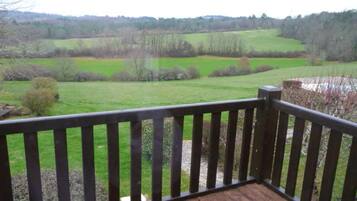 Una terraza de madera con vista a un campo verde y árboles.