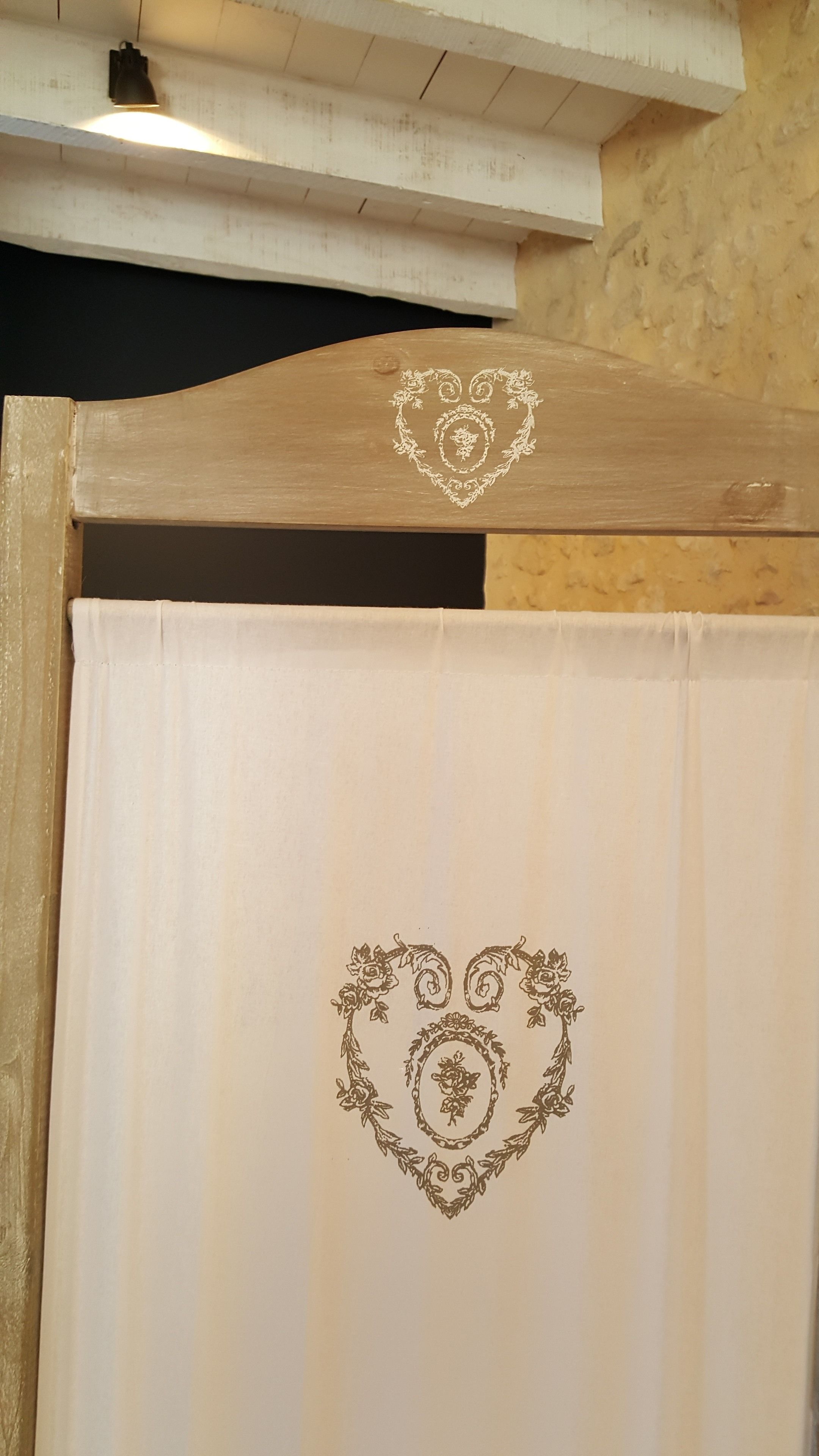 A wooden door with a heart-shaped floral design on a white curtain.