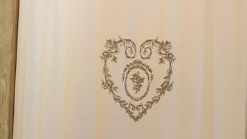 A wooden door with a heart-shaped floral design on a white curtain.